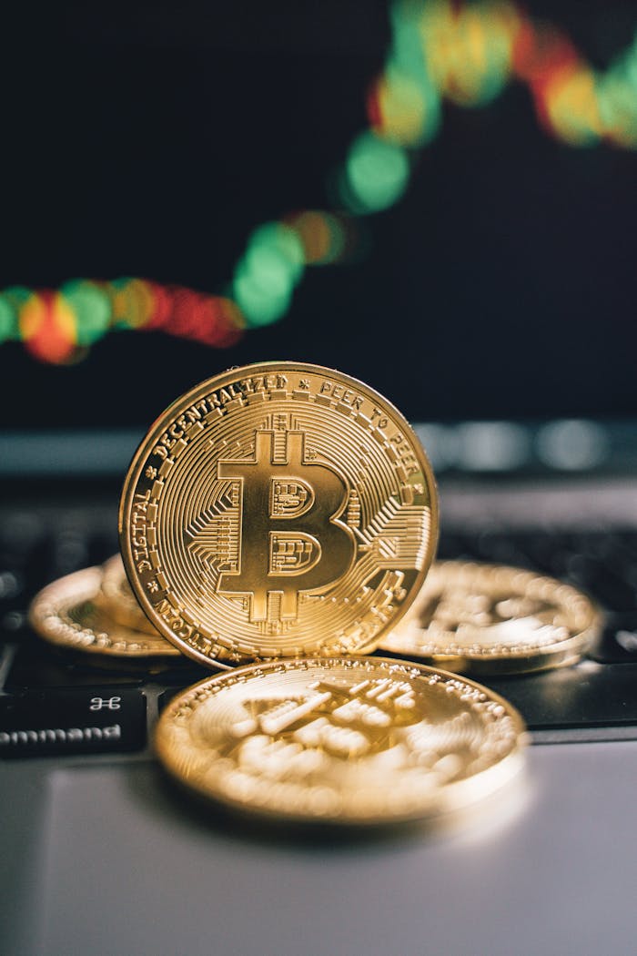 Golden bitcoins on a laptop keyboard with a trading graph in the background.